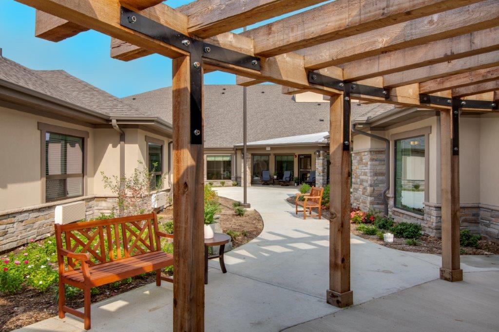 The outdoor walking path, with a shaded pergola and seating, at The Shores at Clear Lake, a senior living community.