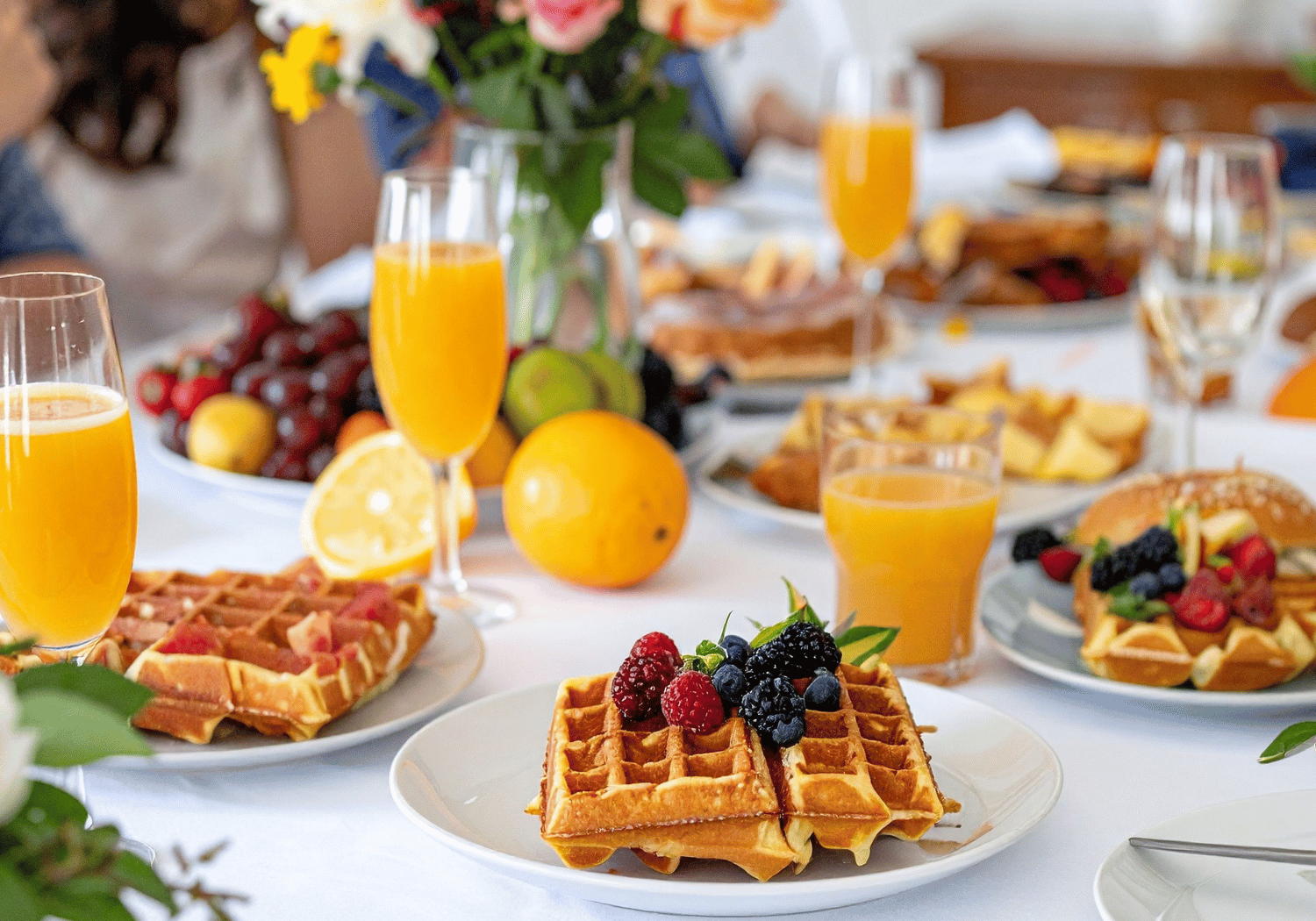 Plate of waffles topped with raspberries and blueberries on a bright brunch table.